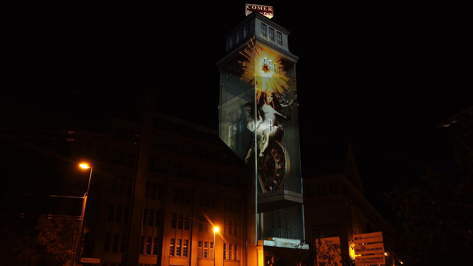 The brick tower of the Peter-Behrens-Bau in Berlin illuminated by a projection mapping at night