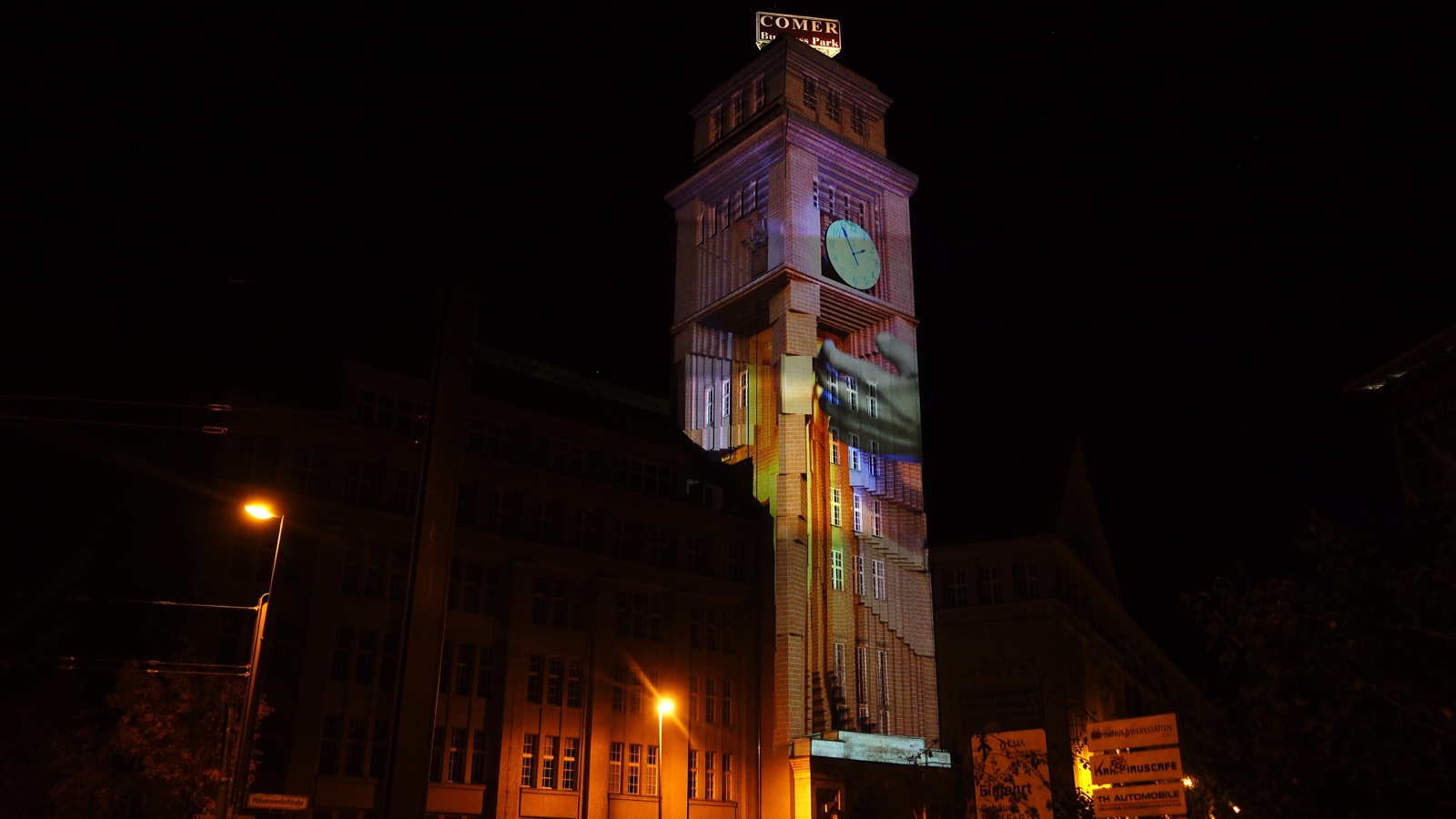The brick tower of the Peter-Behrens-Bau in Berlin illuminated by a projection mapping at night