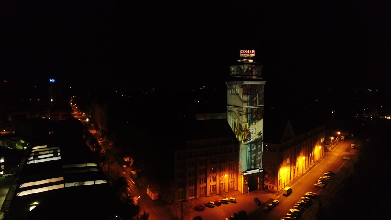The brick tower of the Peter-Behrens-Bau in Berlin illuminated by a projection mapping at night