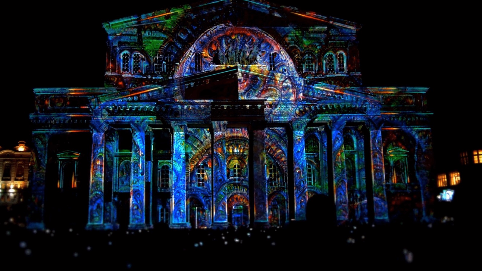 The Bolshoi Theatre in Moscow covered in a dark, textured 3D projection mapping with glowing cracks and colours