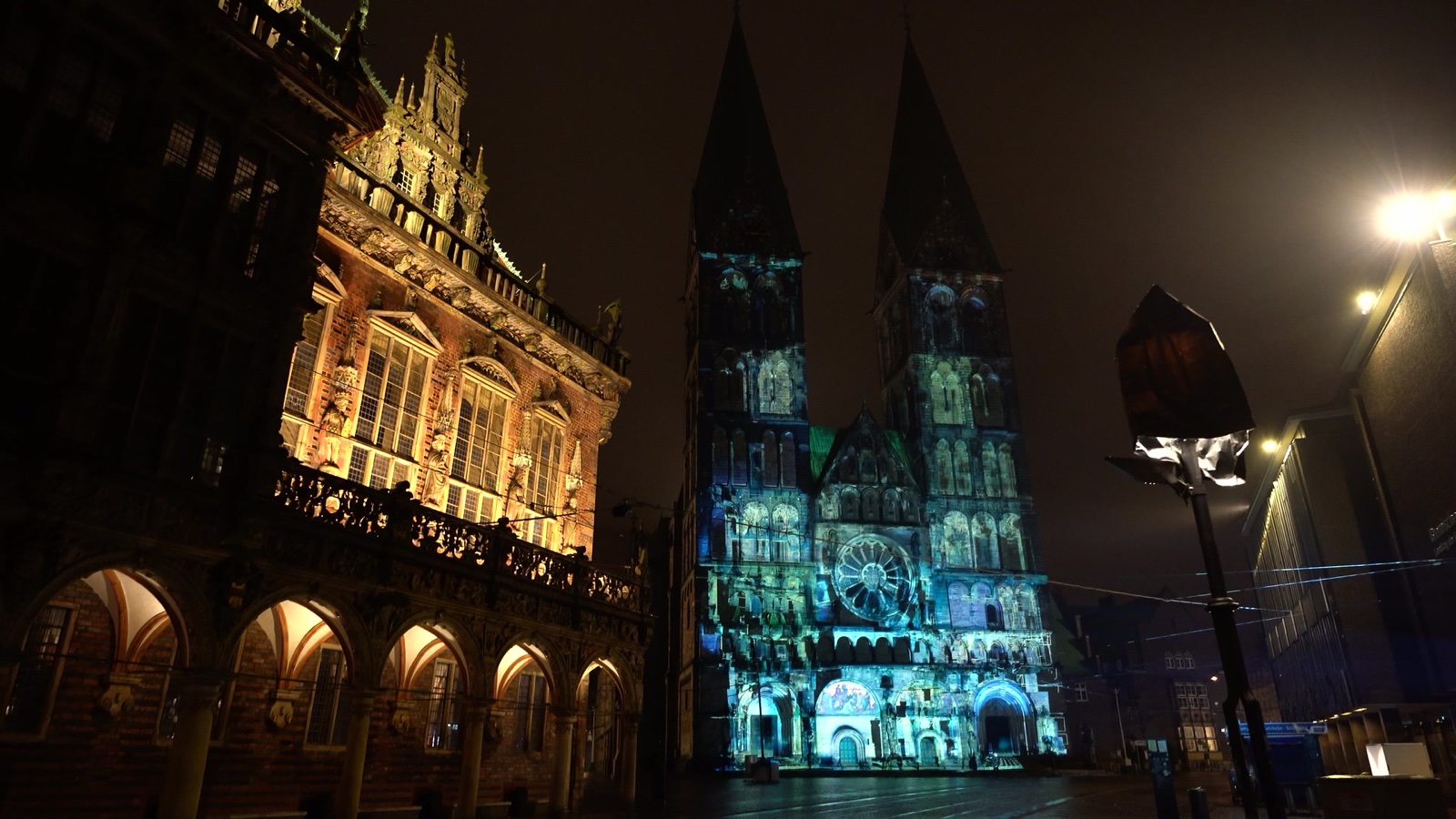 The twin towers of Bremen Cathedral illuminated in blue and gold by a 3D projection mapping at night
