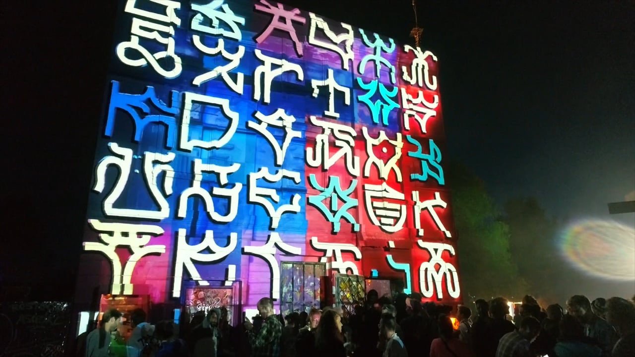 A colourful mural of glyph-like shapes by Räuberkidz animated with projection mapping at Fusion Festival