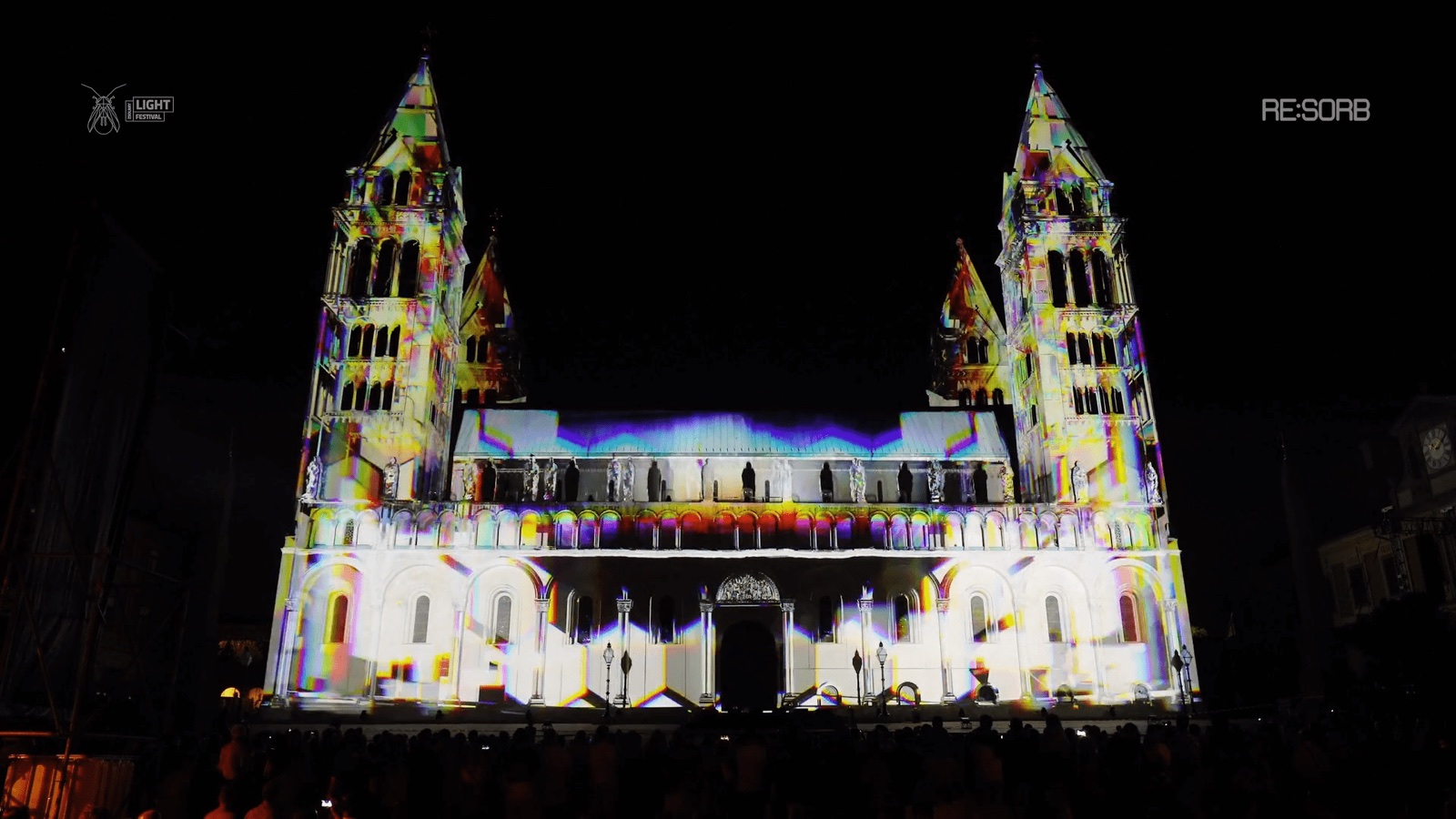 The towers of Pécs Cathedral in Hungary illuminated by a white and yellow 3D projection mapping at night