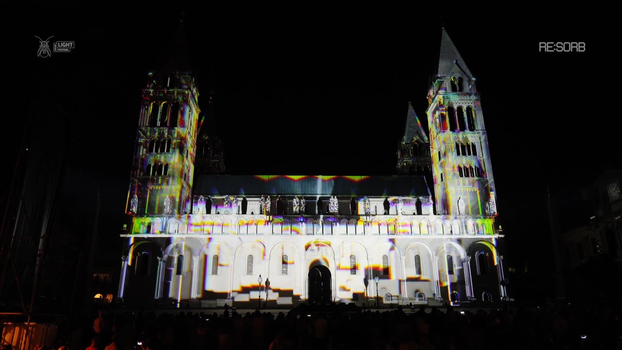 The towers of Pécs Cathedral in Hungary illuminated by a white and yellow 3D projection mapping at night