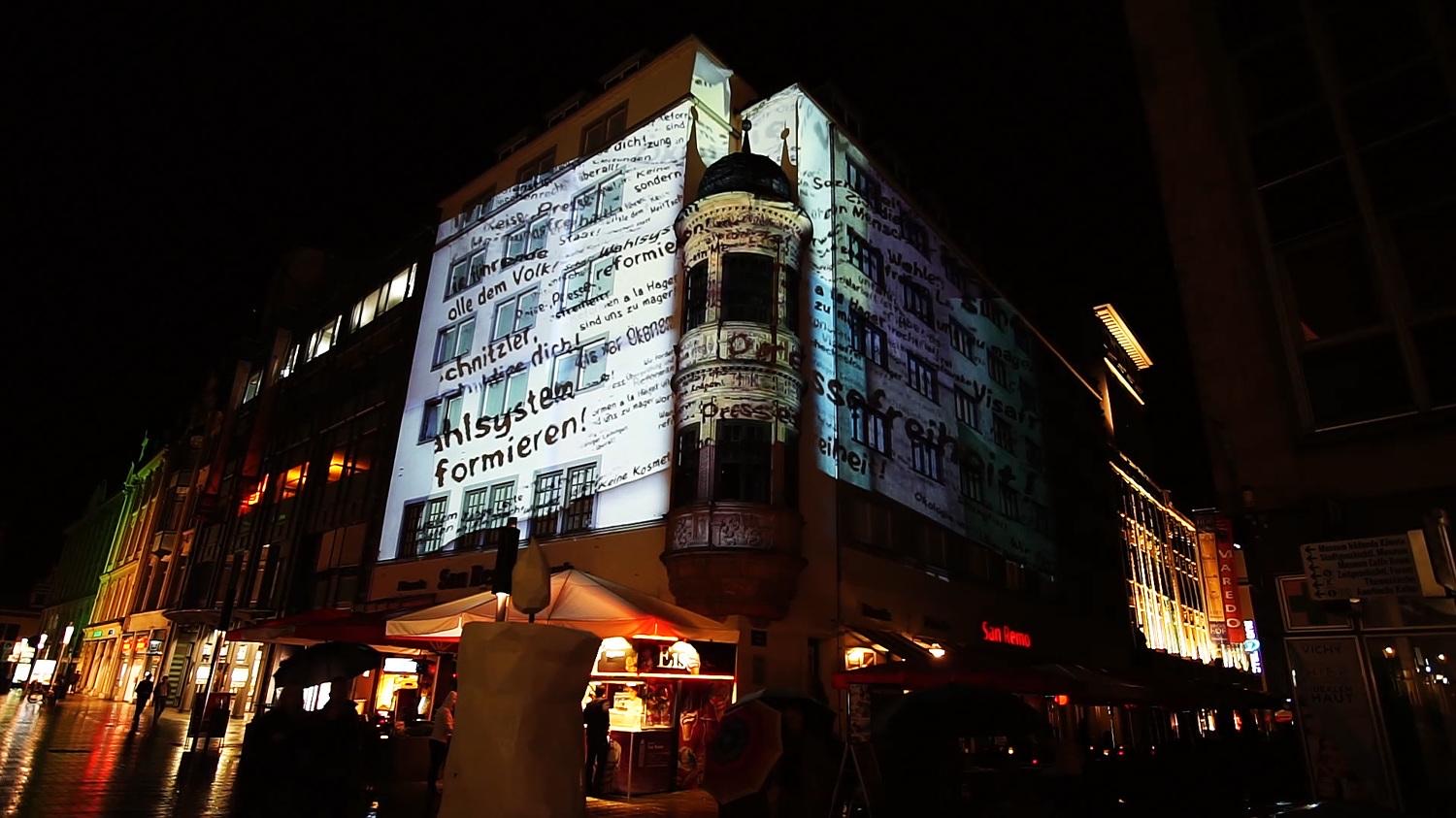 Historic documents and typewritten text projected onto a façade in Leipzig during the Lichtfest