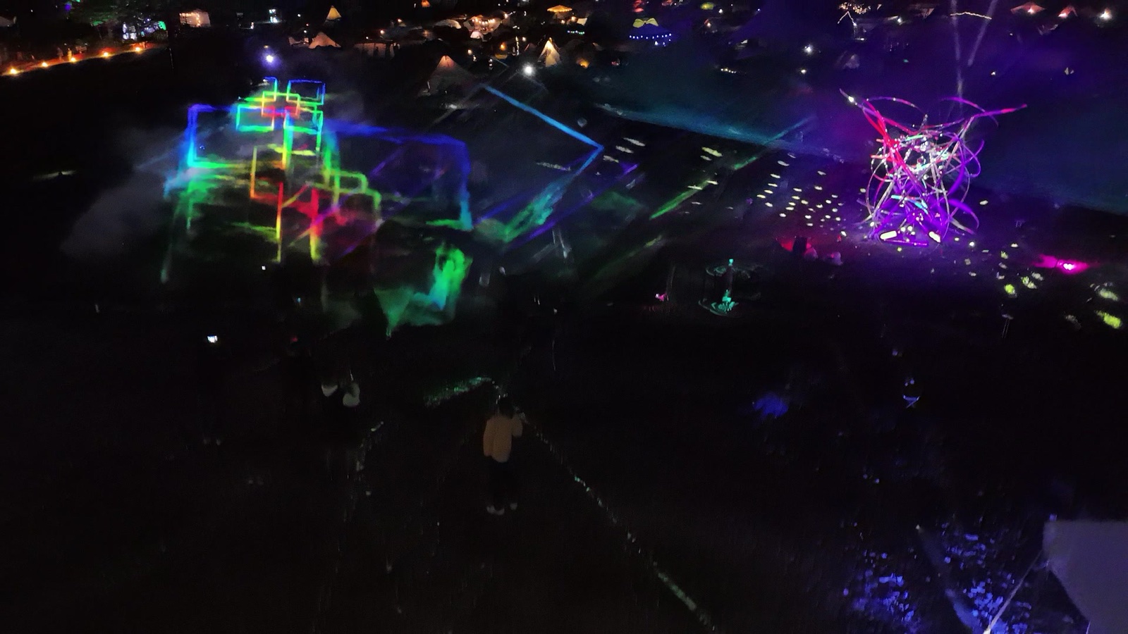 A person standing inside a bright blue holographic light field in fog at night at Re:birth Festival in Japan