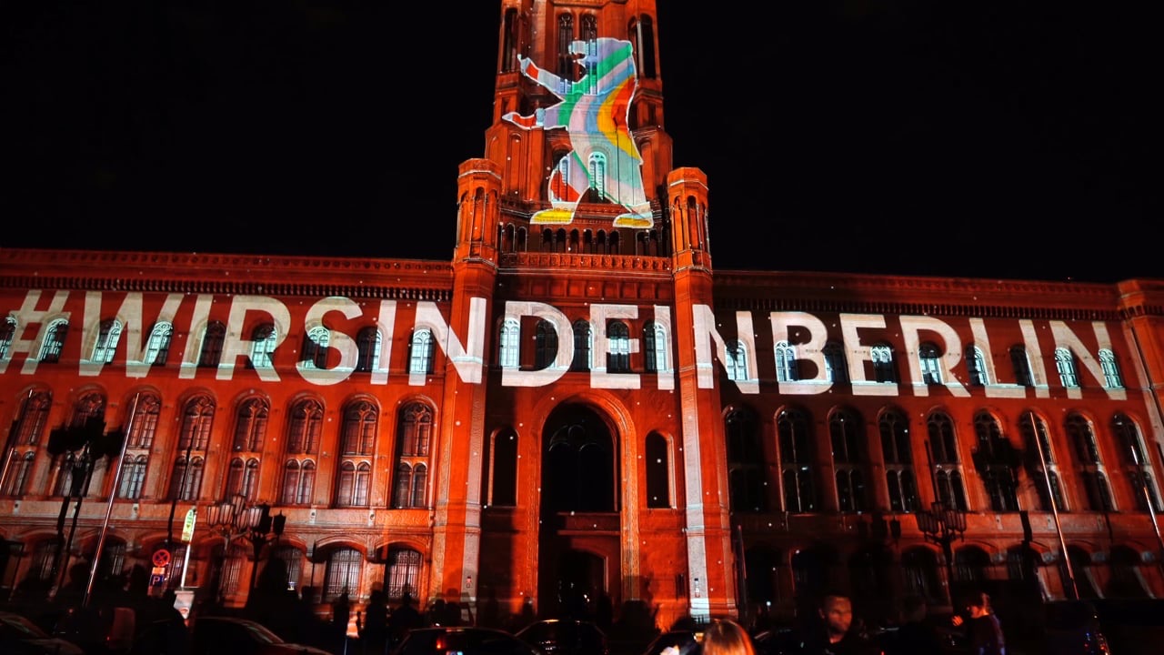 The red brick façade of Berlin’s Rotes Rathaus covered by a projection mapping with the words #WirSindEinBerlin