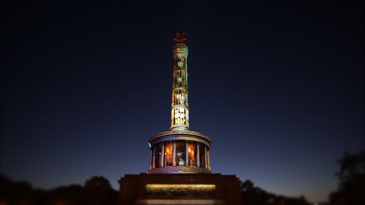 The Berlin Victory Column illuminated in turquoise and blue by a 3D projection mapping at night, filmed in vertical format