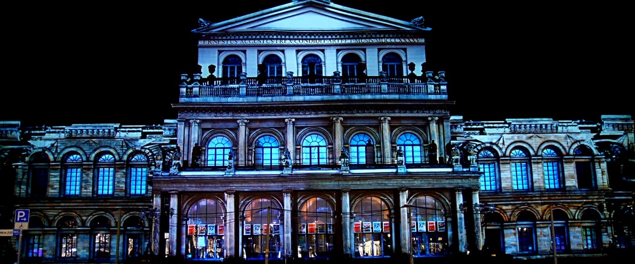 The neoclassical façade of the Hannover State Opera lit in blue and white by a 3D projection mapping