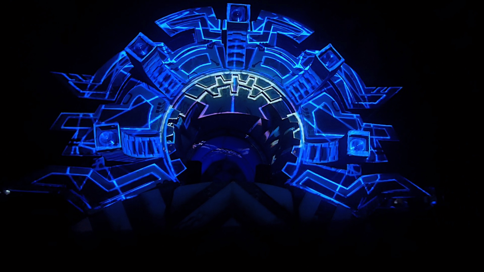 A festival main stage structure at night covered in a blue geometric 3D projection mapping