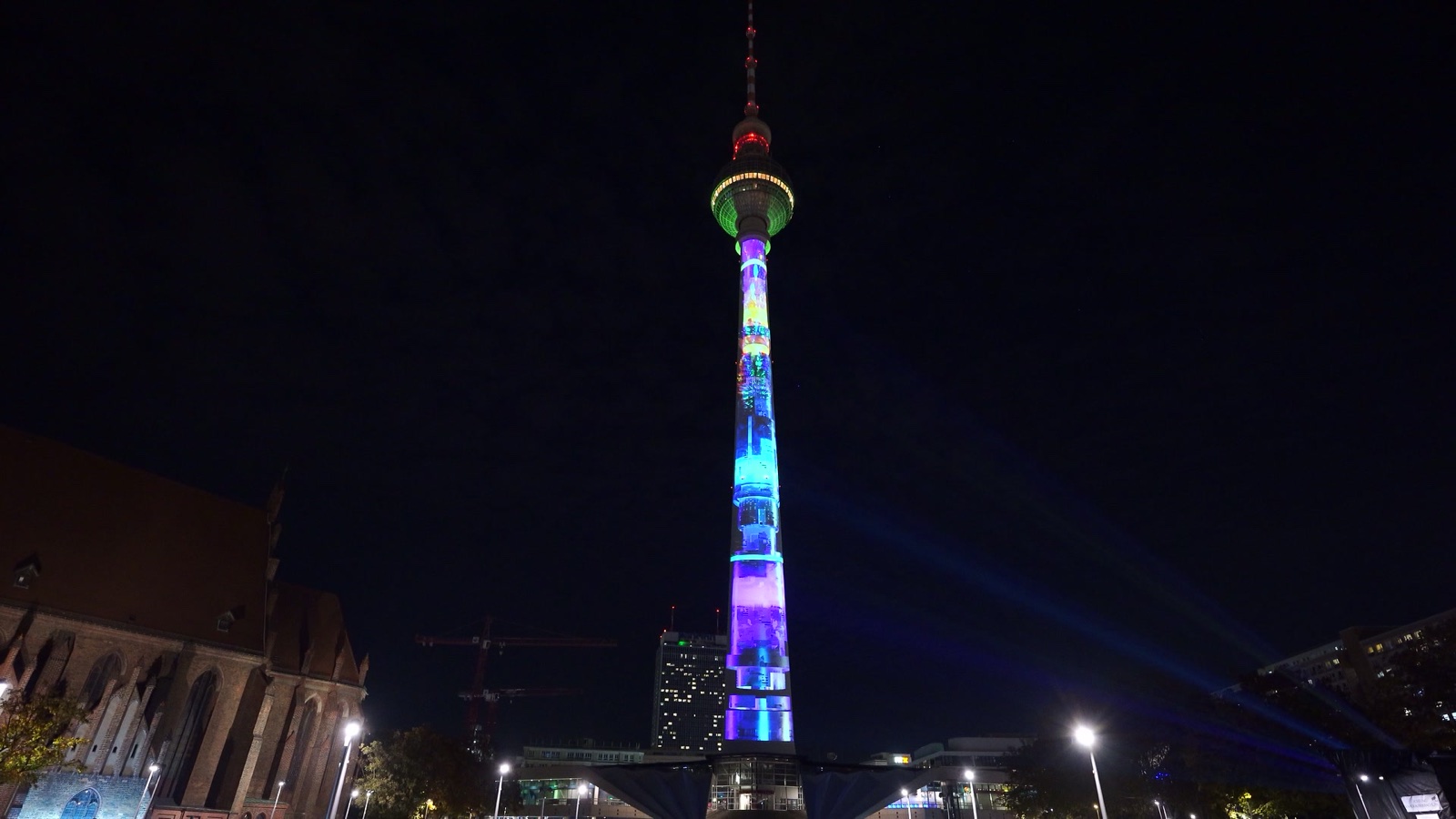 The Berlin TV Tower at night with its shaft and sphere illuminated in blue by a projection mapping, filmed in vertical format