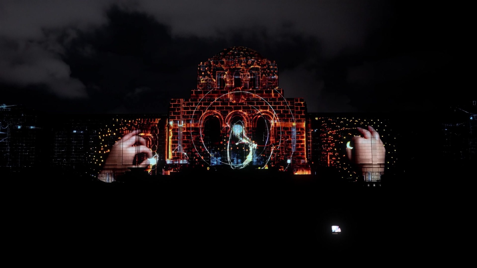 A façade in Tokyo lit by a projection mapping in which a giant face emerges from golden light